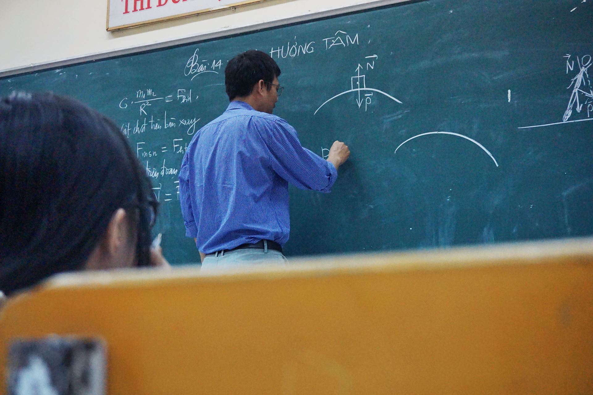 a man sitting in front of a blackboard